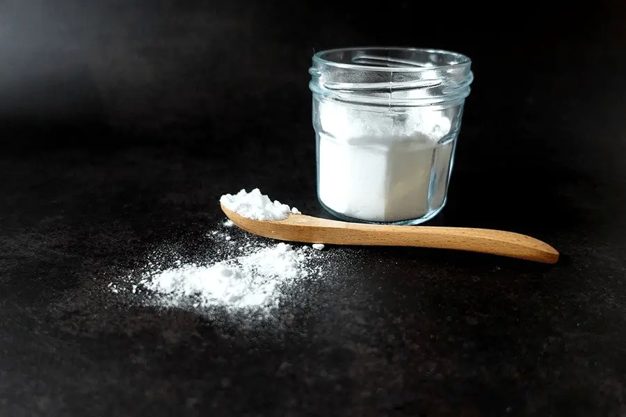 Baking soda in white jar and on a wooden spoon